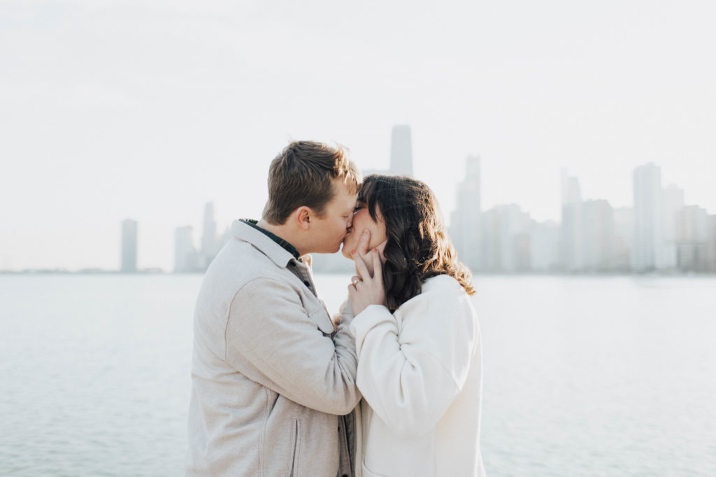 Photo of a couple kissing in front of a body of water.