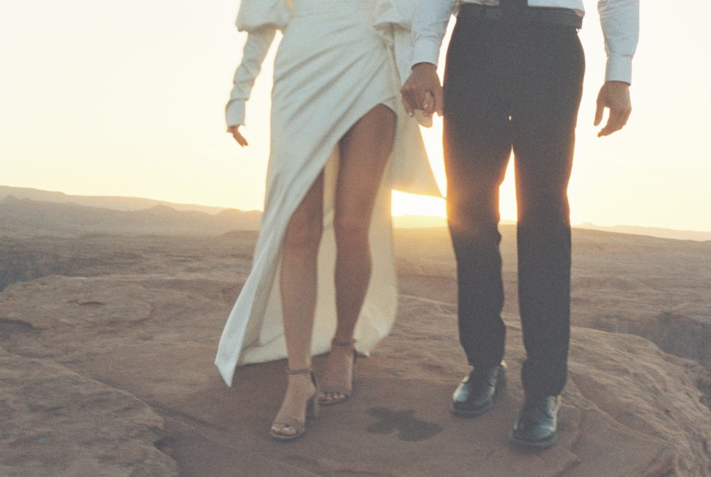 A couple holding hands on top of a cliff.