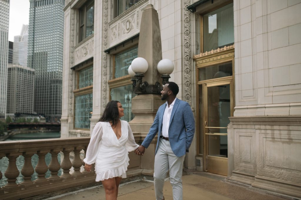 A couple holding hands outside of the Wrigley Building in Chicago, IL.