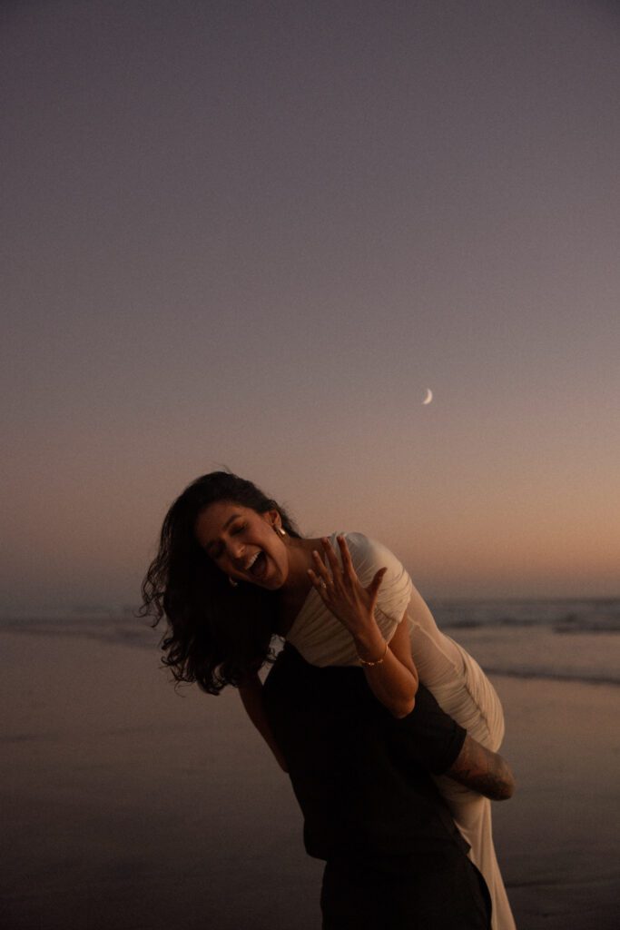 Engagement photos on the beach in Carlsbad during blue hour showing off engagement ring