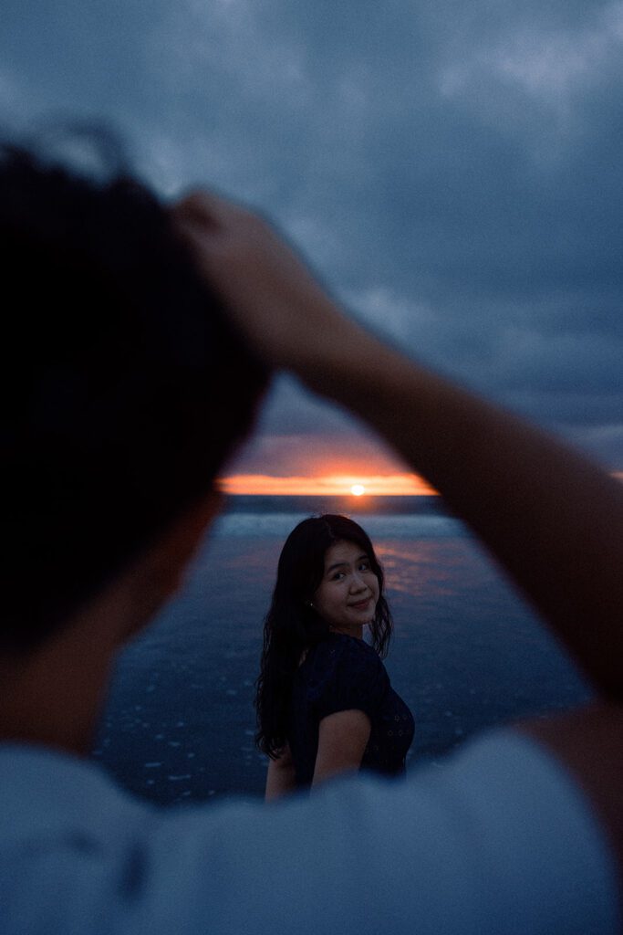 cinematic couples session at solana beach with vibrant colorful sunset painting the sky with unique framing with poses