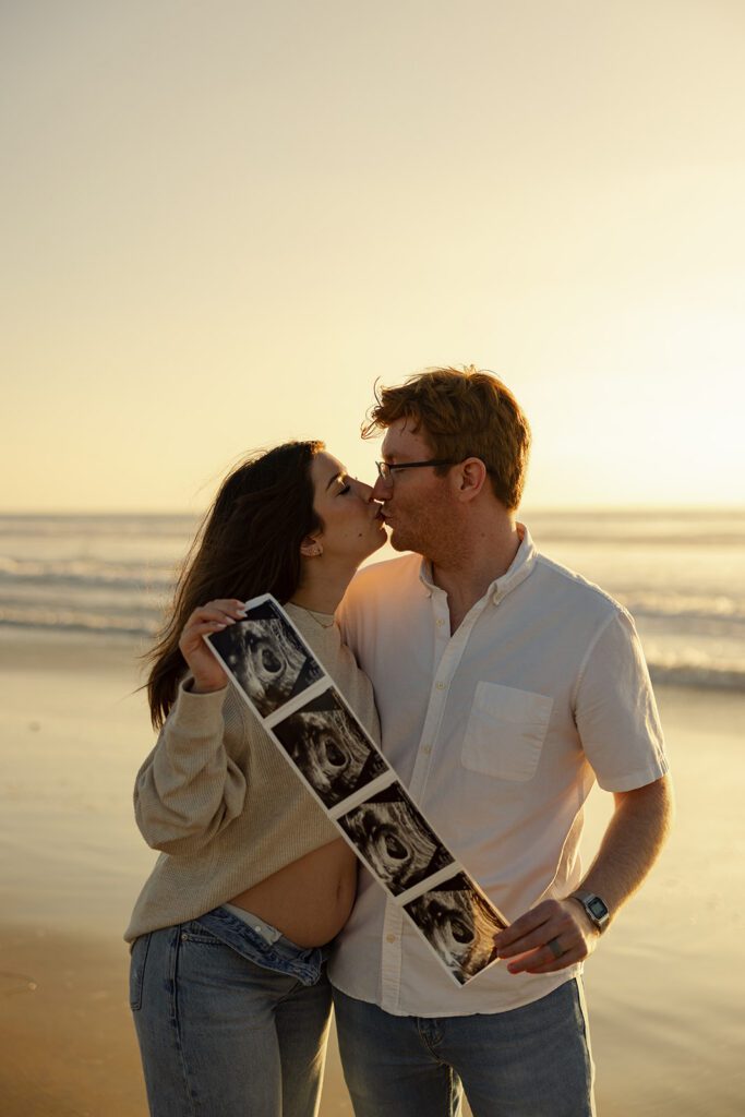 Pacific Beach Pregnancy Announcement in San Diego, CA at golden hour. couple poses with ultrasound to announce their first pregnancy
