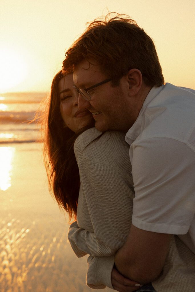wrapped up in love. couple shares a romantic embrace during their pacific beach pregnancy announcement