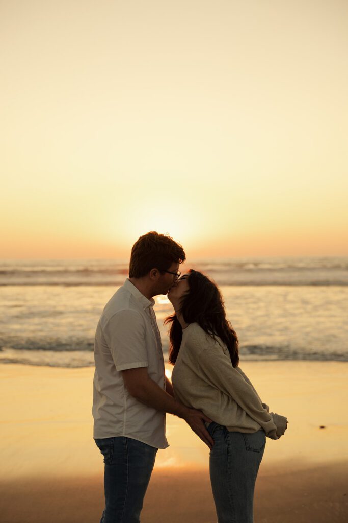 wrapped up in love. couple shares a romantic embrace during their pacific beach pregnancy announcement