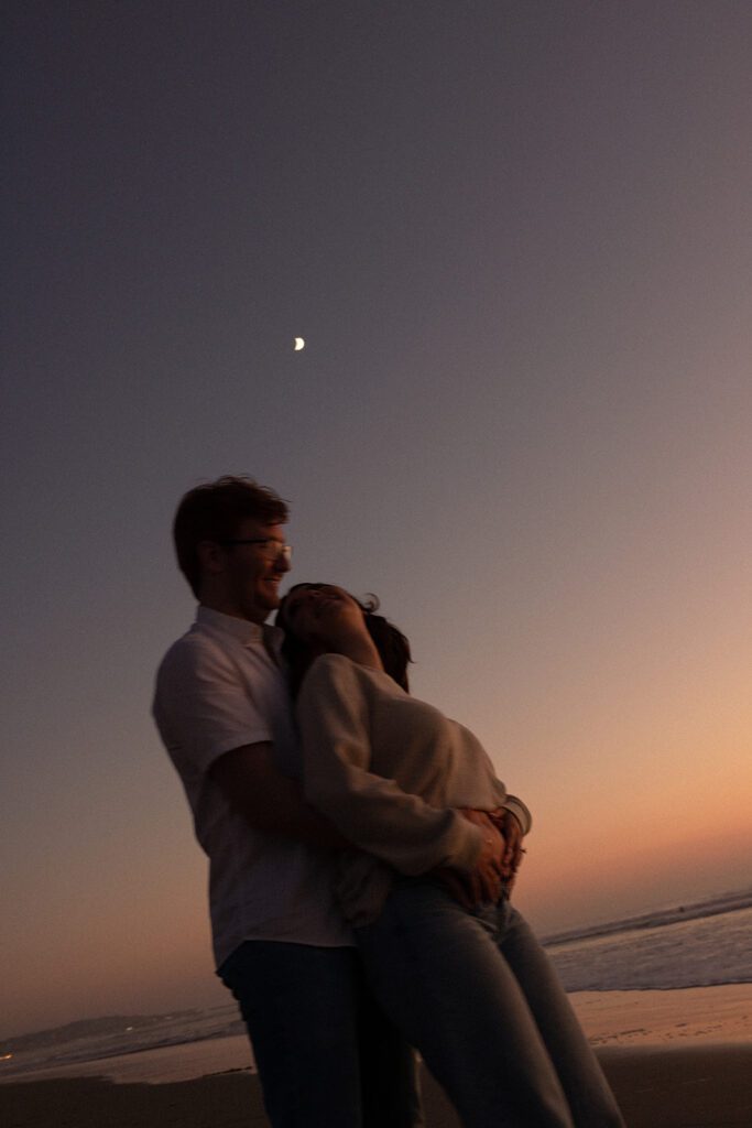 wrapped up in love. couple shares a romantic embrace during their pacific beach pregnancy announcement. cinematic pregnancy photos