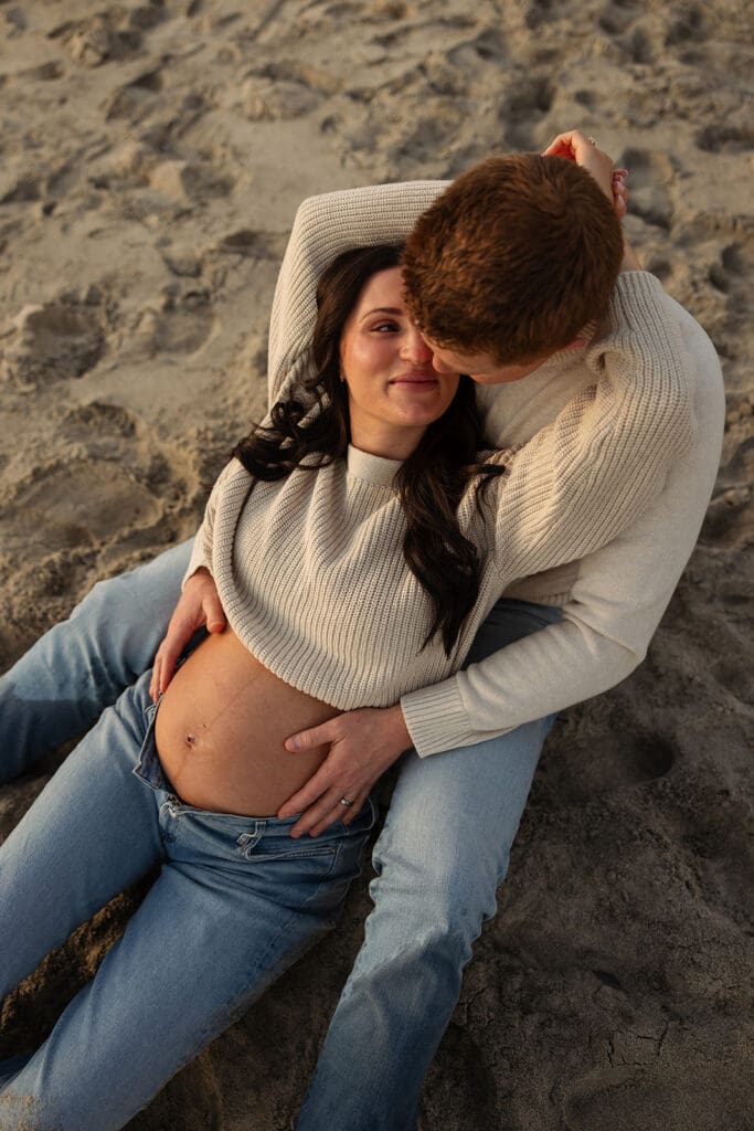 gorgeous blue skies, bird flying over the ocean and couple laying in the sand for their maternity photos