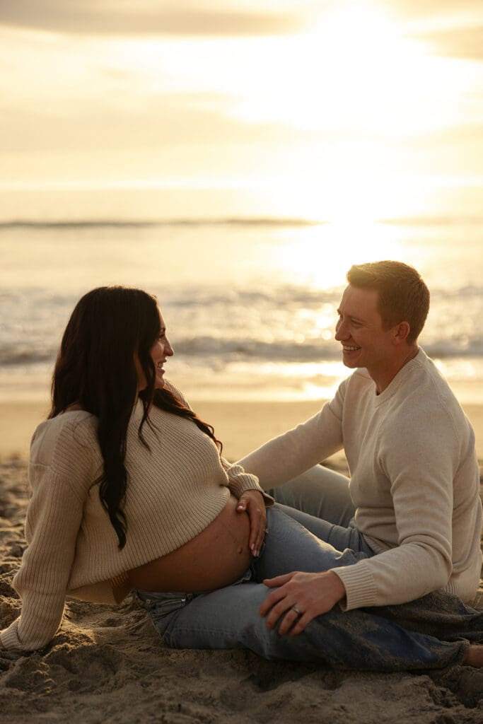 gorgeous blue skies, bird flying over the ocean and couple laying in the sand for their maternity photos
