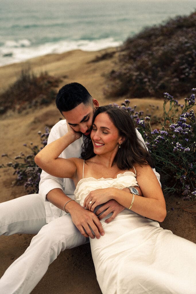 cliffside engagement photos on the coast of california surrounded by purple flowers