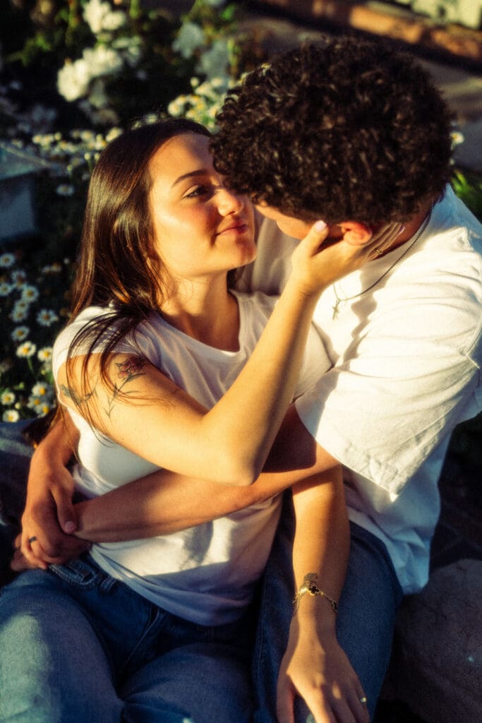 couple cuddles up under a palm tree under the beautiful blue san diego skies