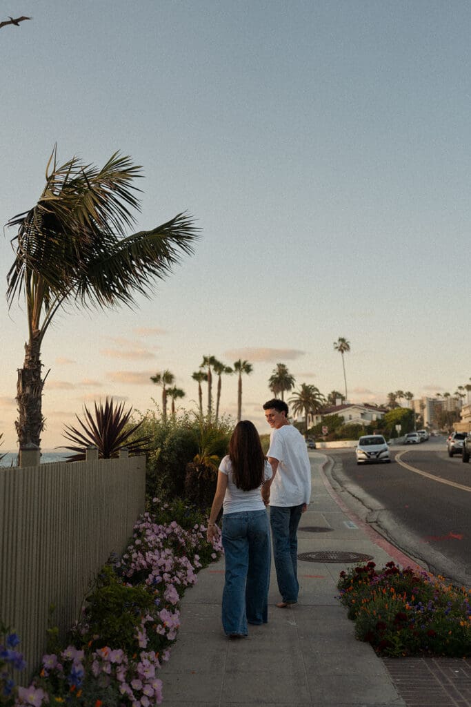 san diego couples session along the coast - couple walking underneath the beautiful palm trees
