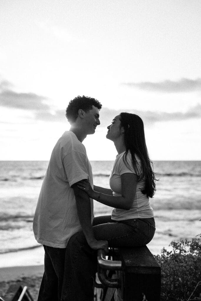 couple shares a moment in the boardwalk leading up to the beach