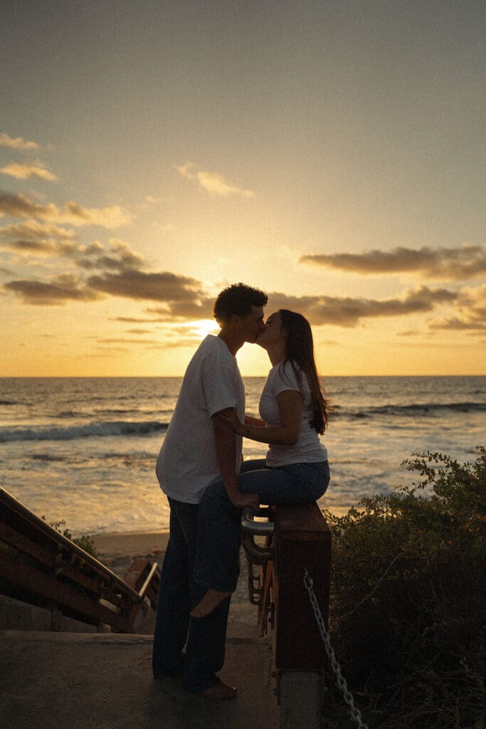 couple shares a moment in the boardwalk leading up to the beach
